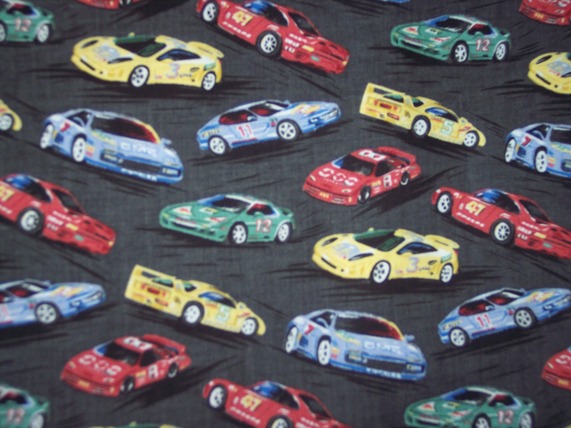 Race cars in light primary colors on black pavement