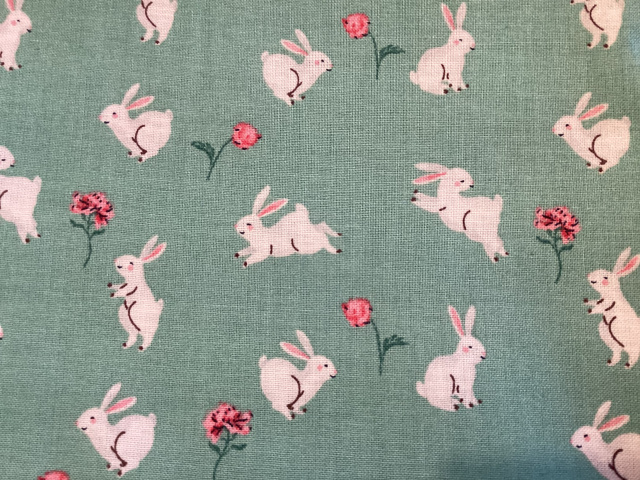 Cream bunnies hopping among pink stem roses on a sage background 