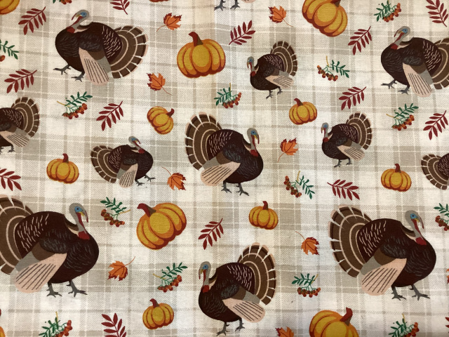 Turkeys, pumpkins and leaves on a beige plaid background