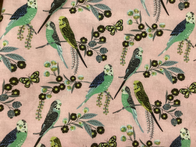 Parakeets that are green, yellow and blue on floral branchest fo the same color on pink background